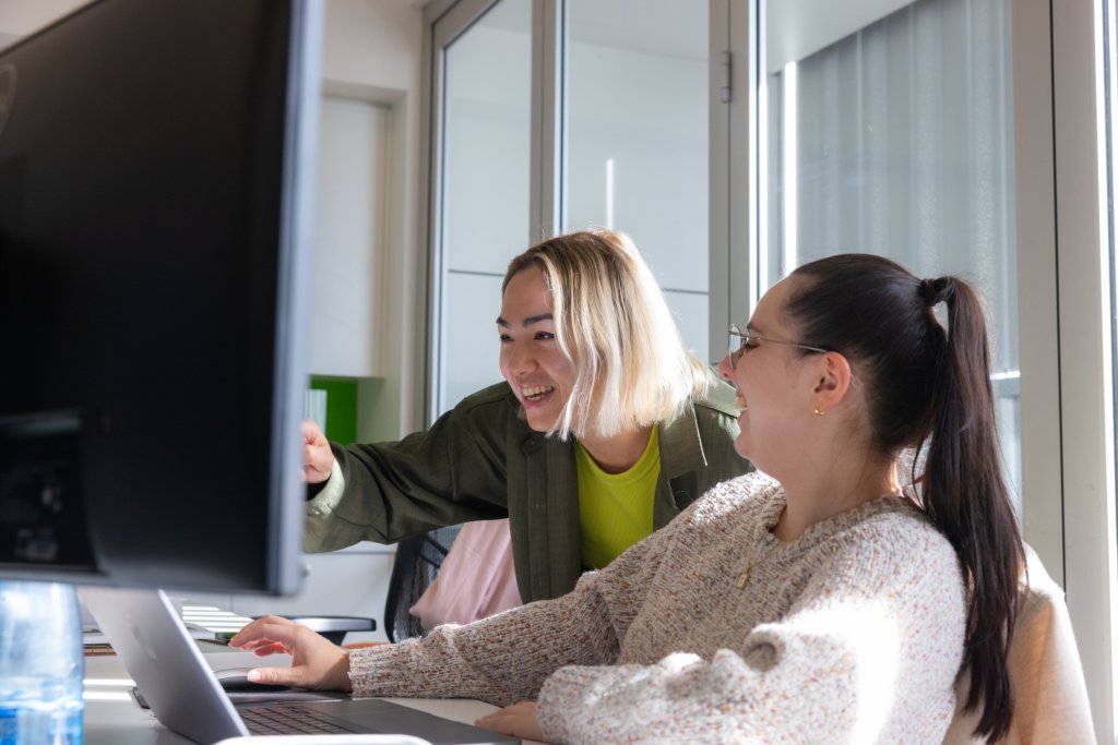 Two digital signage solution experts employed by Coates Group working behind a computer.